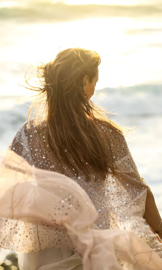Christine looking out to sea as her shawl swirls around her